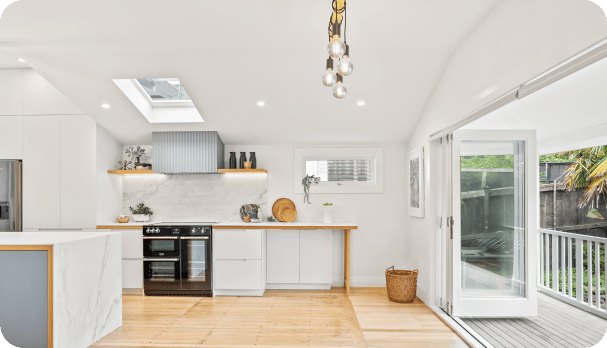 A modern kitchen with a skylight above, complemented by rich wooden floors.