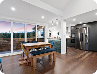 Auckland Home Builders Open-plan kitchen and lounge area with modern cabinetry, stylish lighting, and contemporary furnishings.